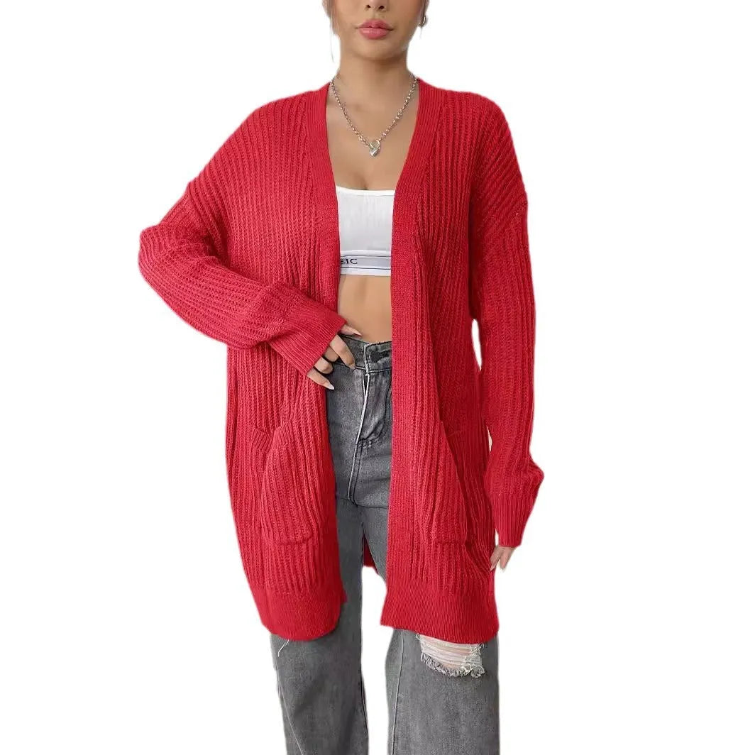 A woman wearing a dark green, mid-length acrylic cardigan with two front pockets.