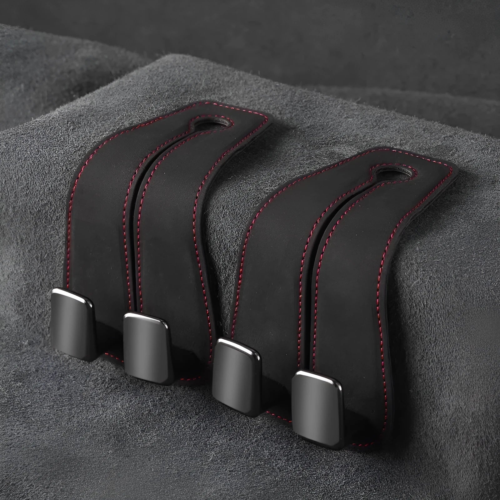 Alloy car seat hook clipped to headrest post in black, showing flip-down design for bag storage.