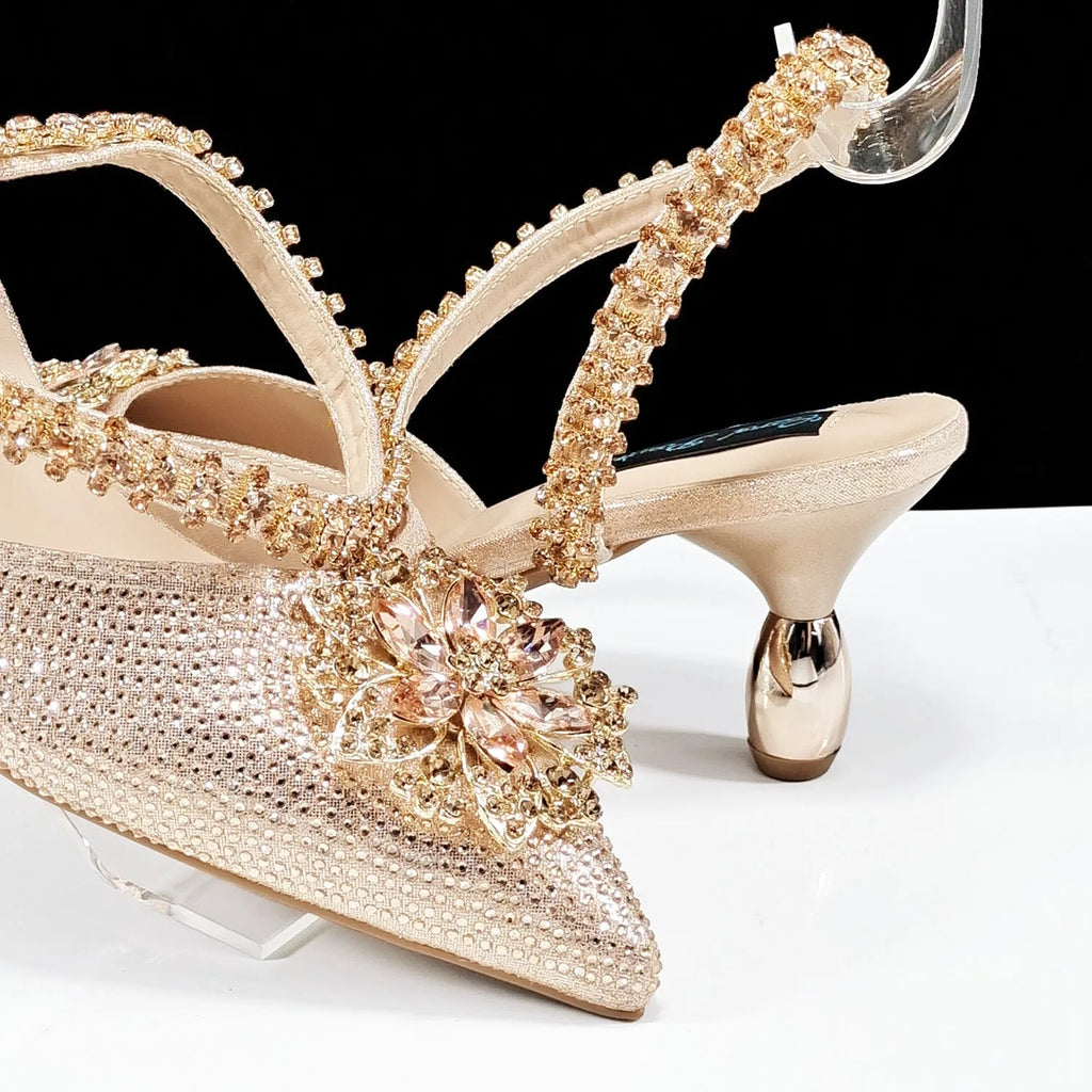 Black high heel ankle strap shoes with floral buckle and matching rhinestone clutch bag.