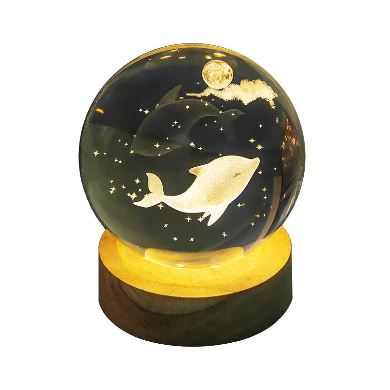 Transparent crystal ball night lamp with 3D carved jellyfish design, lit with soft blue glow on a round base.
