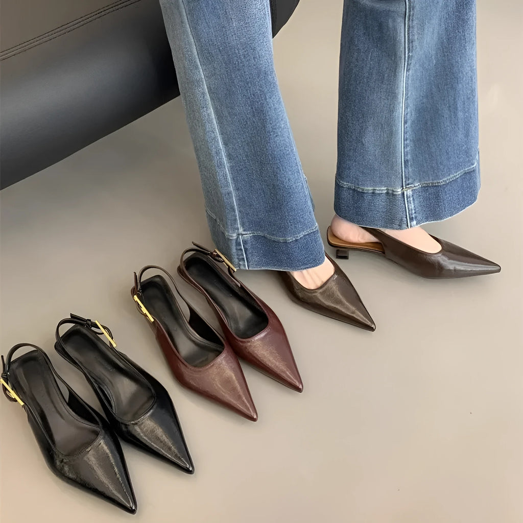 Women's black pointed toe leather strap shoes with a low rubber heel shown from the side.