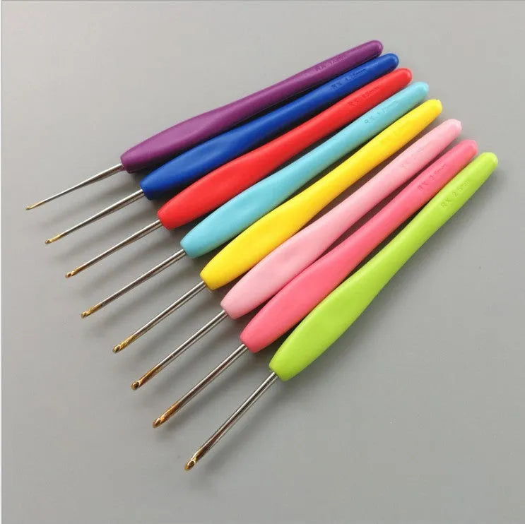 Set of 16 coloured crochet hooks with two handle types laid next to a grey PU fabric storage bag.