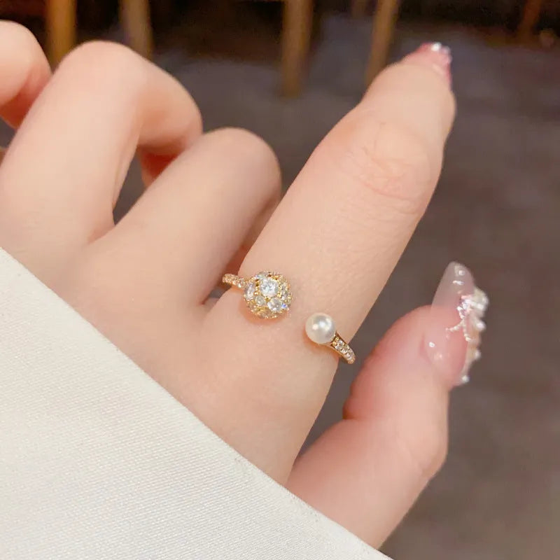 Gold or silver coloured open-end women's ring with round zircon stones and pearl detailing on a geometric band.