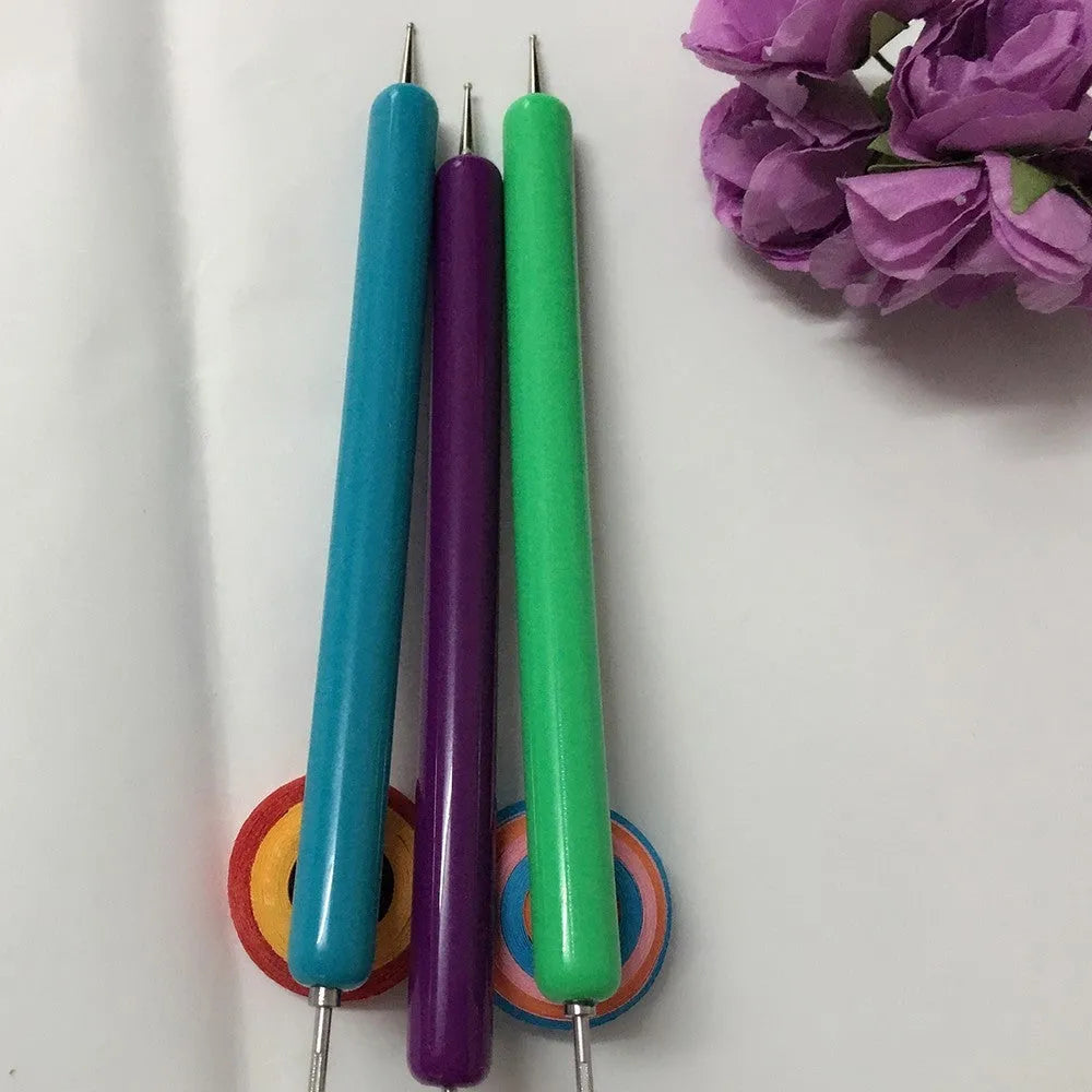 Five purple quilling pens with slotted tips and a stylus laid out on a surface