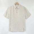 Man wearing a loose-fit light grey linen V-neck short-sleeve top on a summer day.