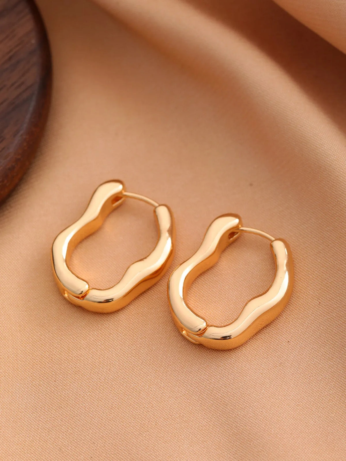 Smooth geometric hollow metal earrings for women in gold finish on a white background
