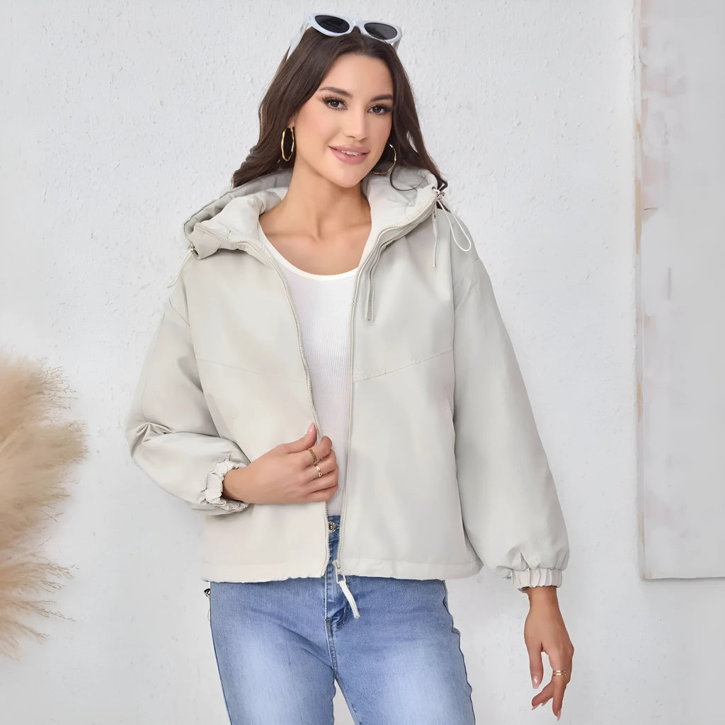 Grey loose-fit women's hooded shell jacket with long sleeves on a hanger.