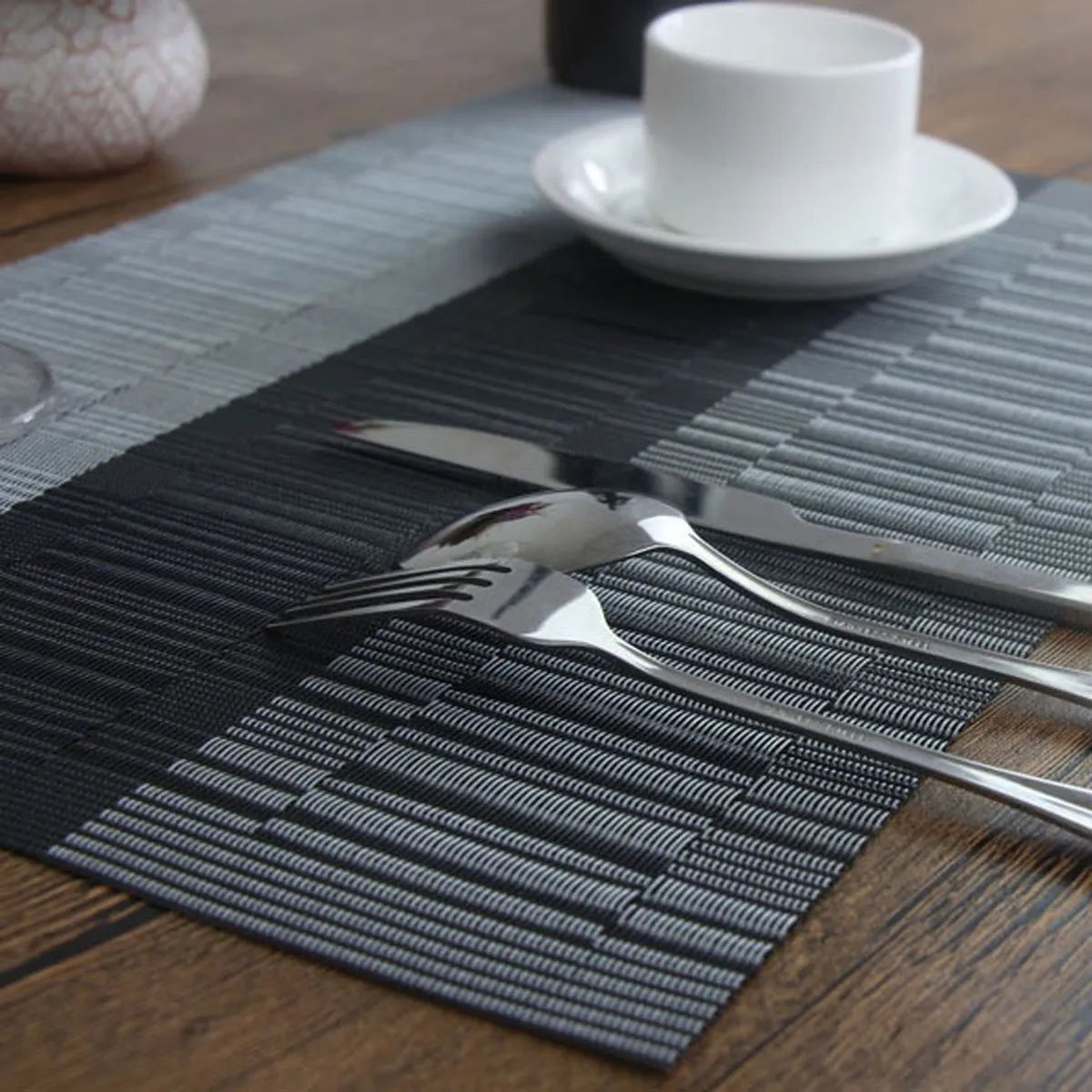 Modern PVC placemat in gradient bamboo design on a wooden dining table.