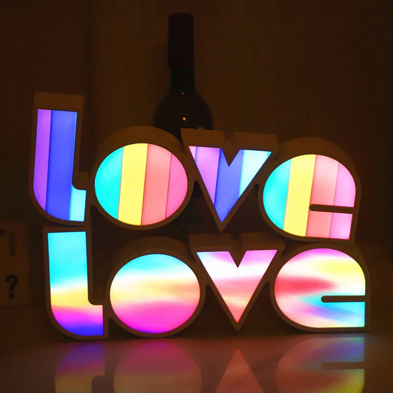 LED LOVE light with rainbow-coloured plastic lampshade on a desk
