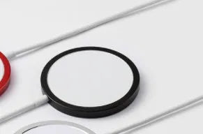Silver metal Magsafe-compatible magnetic wireless charger for iPhone on a wooden table