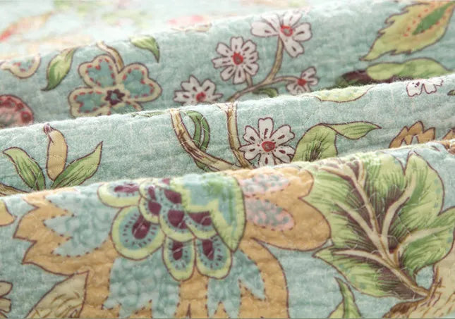 Blue American floral pattern quilted cotton bedspread set on a bed, showing pillowcases.
