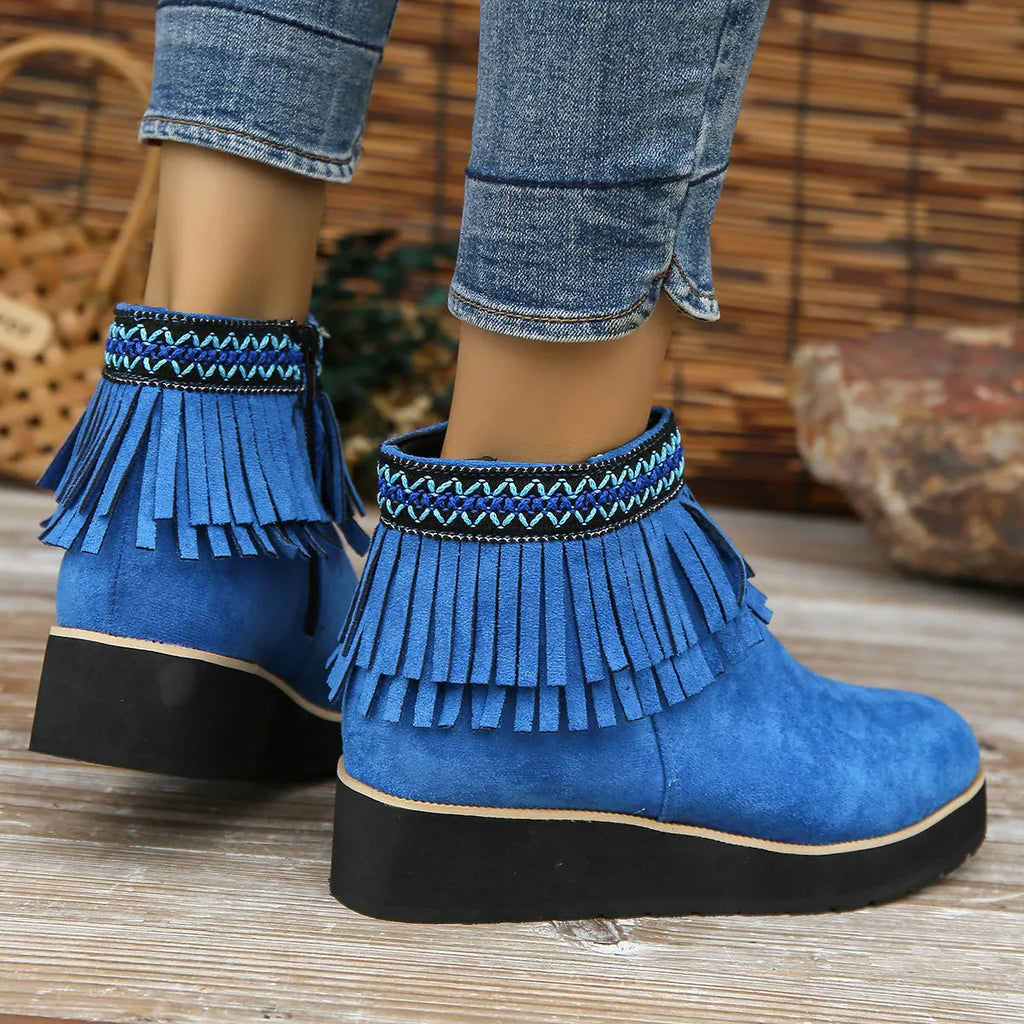 Women's black suede wedge bootie with a thick sole, side zipper, and tassel detail.