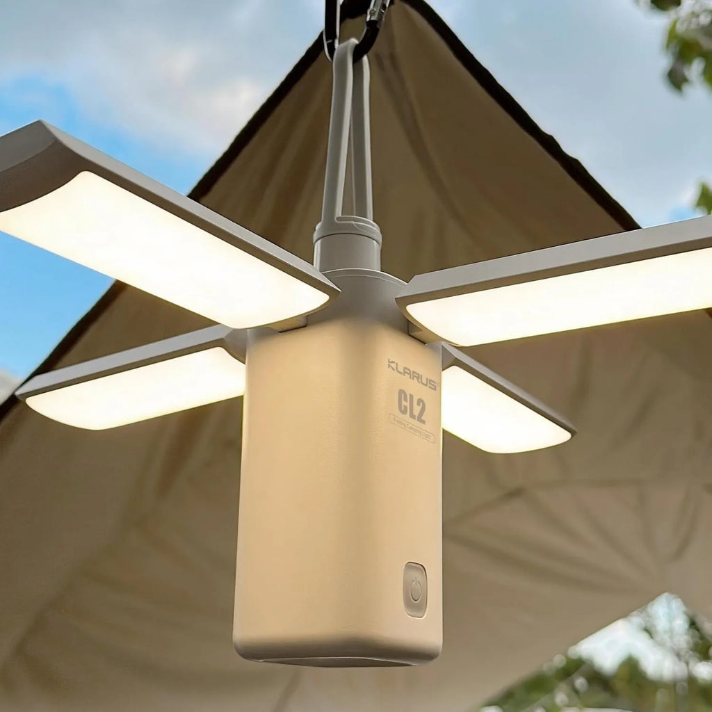 White and green rechargeable LED campsite lamp with charging cable on outdoor picnic table.
