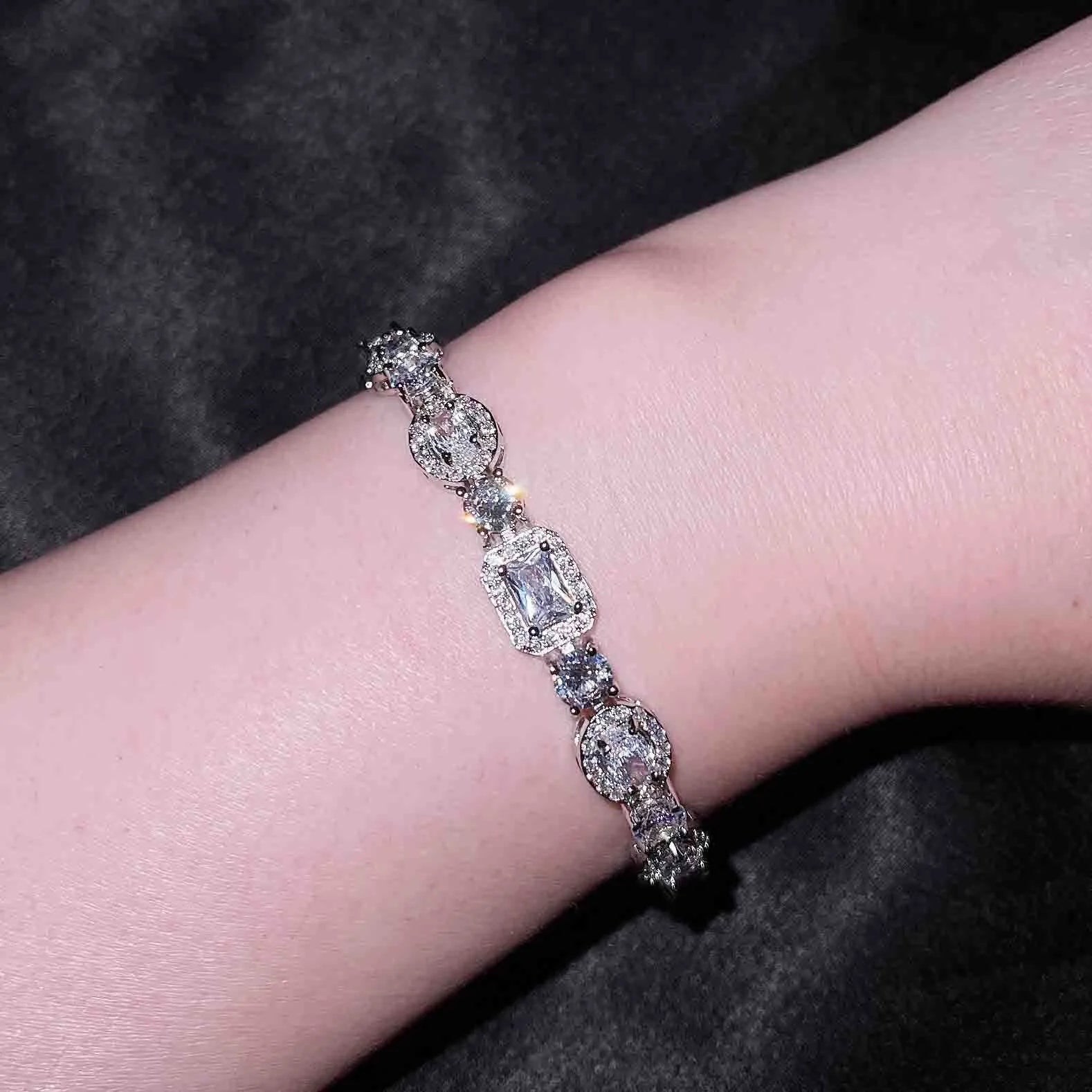 Close-up of women's geometric silver bracelet with sparkling cubic zirconia stones on a wrist, showing adjustable clasp.