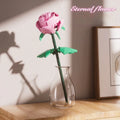 Rose assembled from small particle plastic building blocks in pink, red, or blue