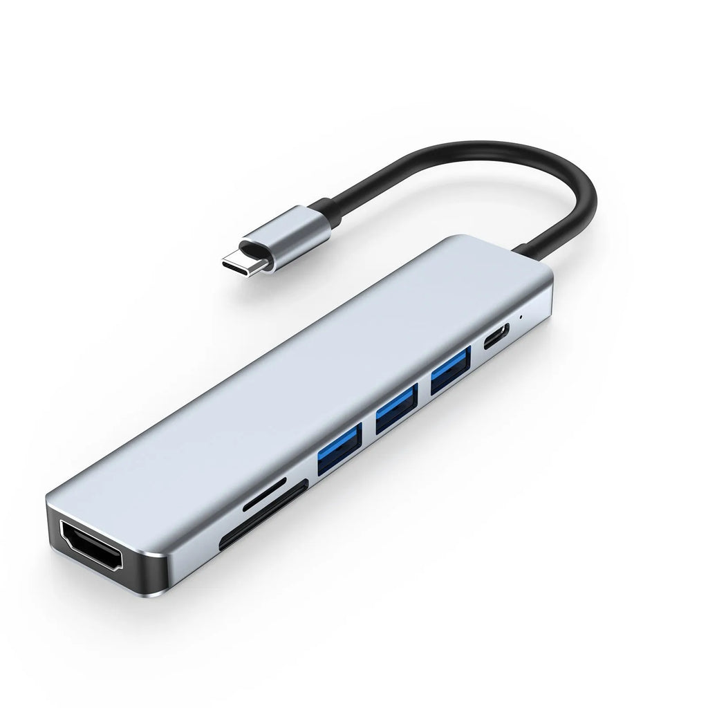 Silver seven-port type-C USB expander hub with a short black cable on a wooden desk.