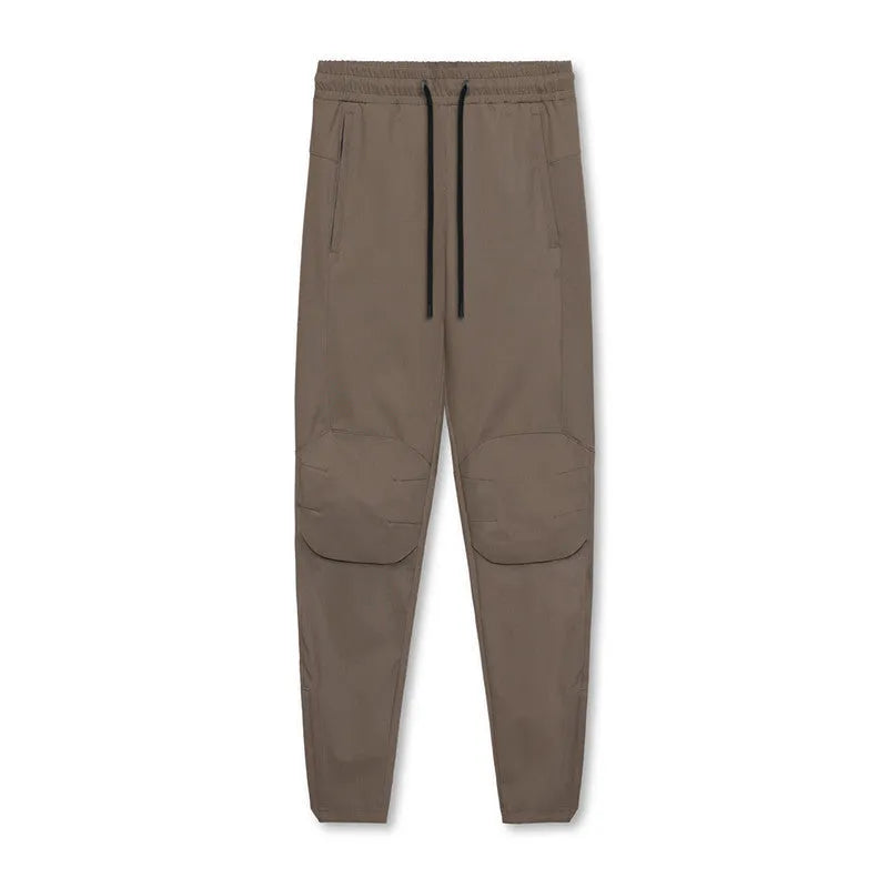 Man wearing dark grey loose-fit fitness trousers with tied ankle cuffs, suitable for gym training.