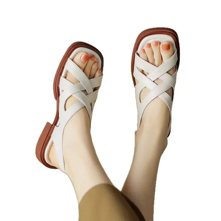 Women's glossy patent leather sandals with a square toe and low heel on a solid colour background.