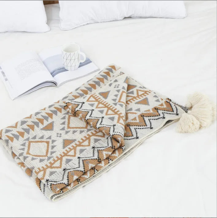 Bohemian style acrylic sofa cover blanket with tassel trim in a geometric pattern colour option.