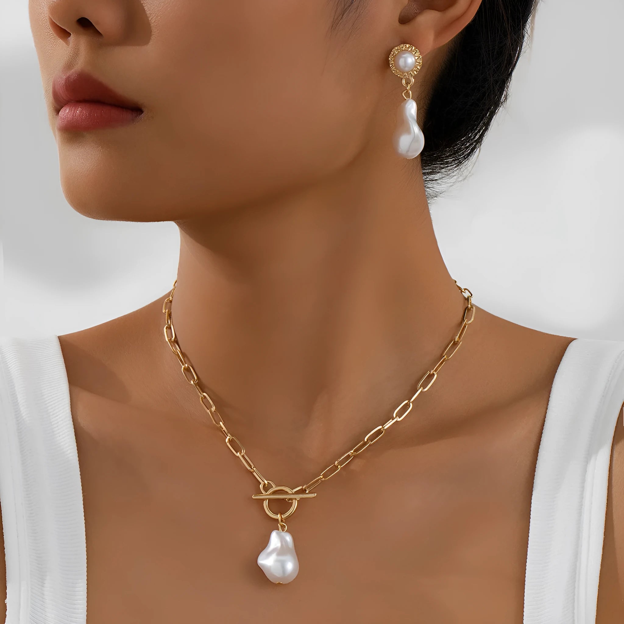 Gold-coloured retro baroque pearl necklace and matching ear studs set on a display.