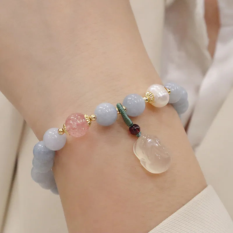 Gold plated bracelet with a detailed artificial crystal charm pendant on a woman's wrist.
