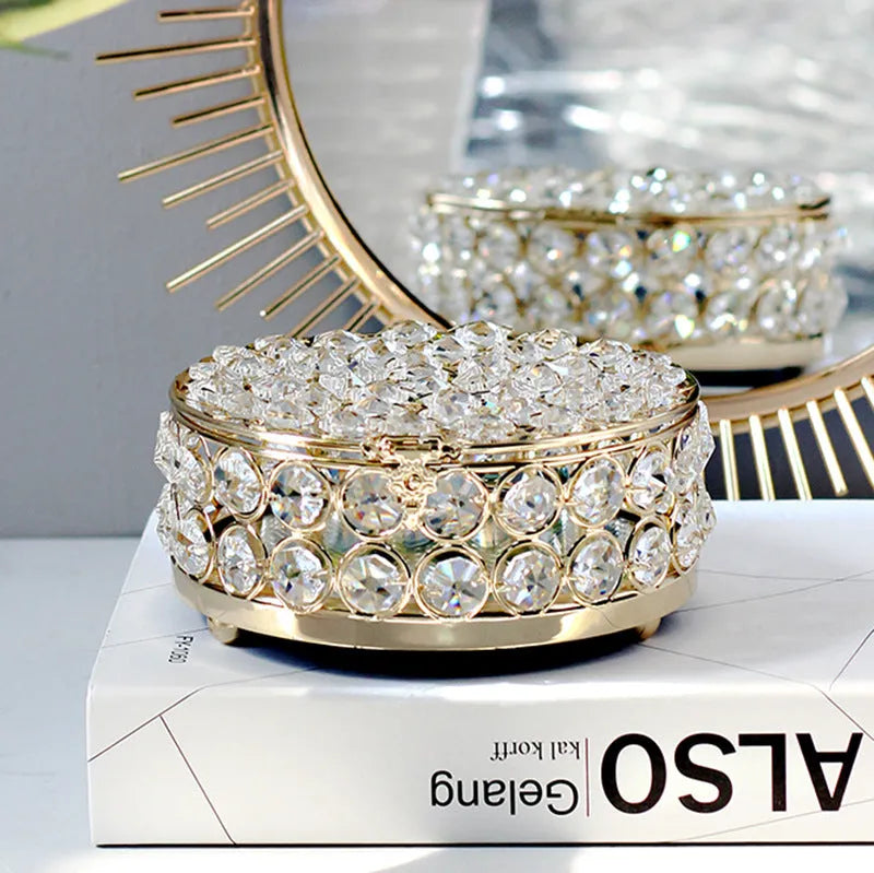 Crystal clear glass jewelry box with French gold metal frame on a table.