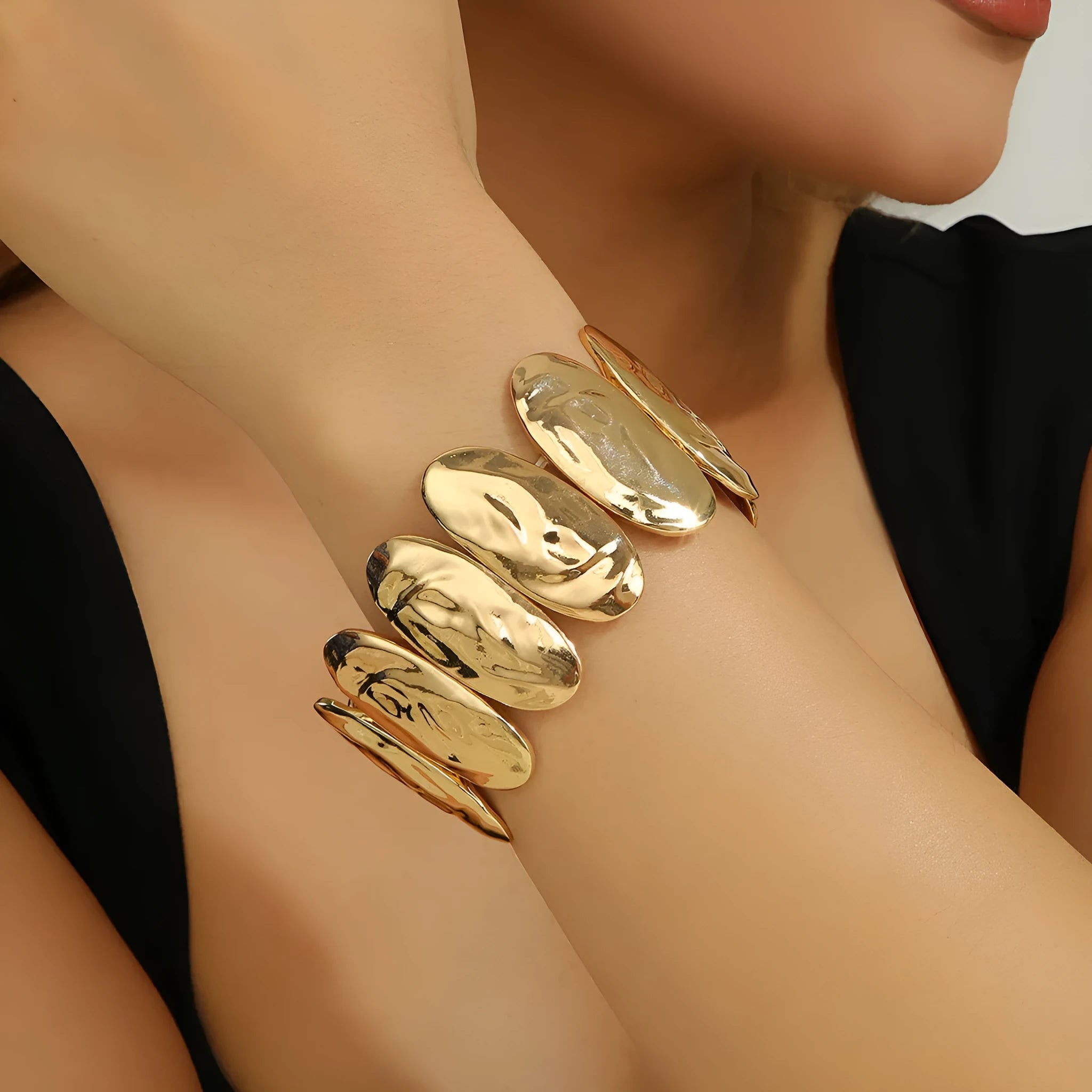 Gold exaggerated elliptical cuff bangle with 4mm band width on a neutral background