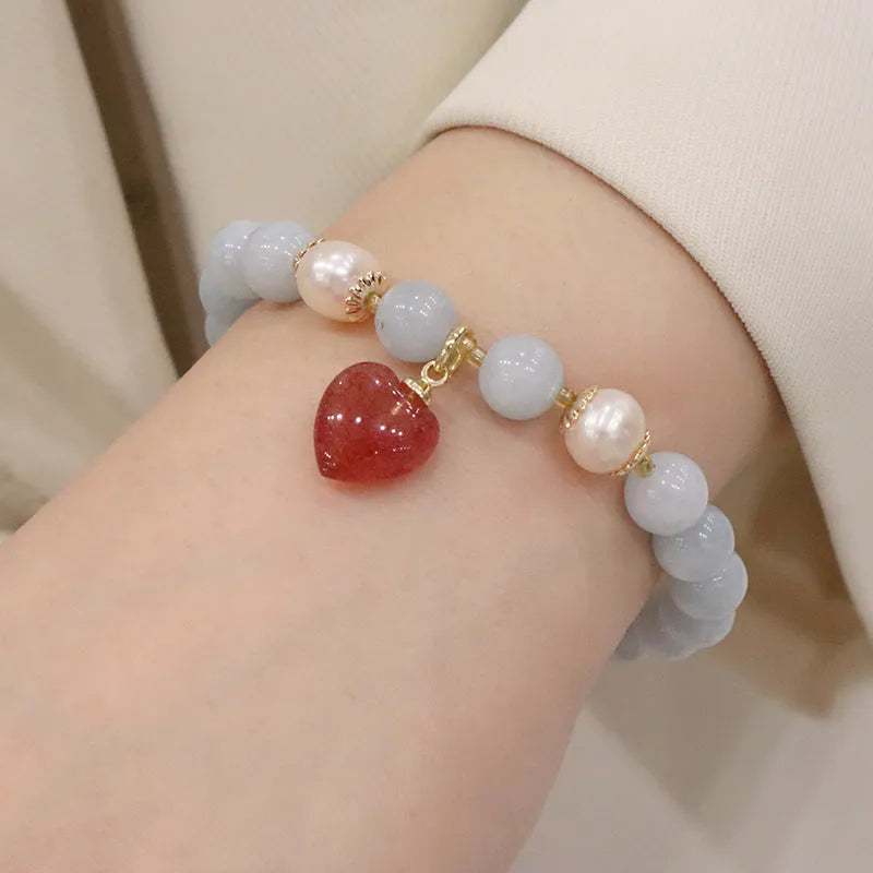 Gold plated bracelet with a detailed artificial crystal charm pendant on a woman's wrist.