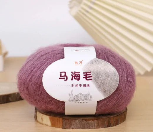 A ball of mohair yarn in a selected colour next to a hand-woven scarf example, showcasing the DIY kit.