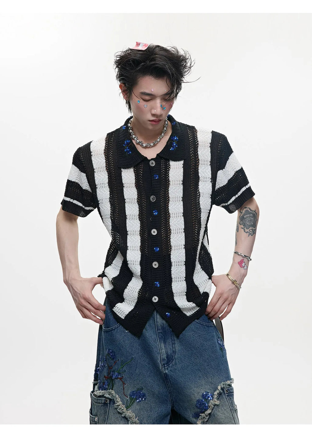 Man wearing a red and black patchwork striped knitted short-sleeved shirt with a loose fit.