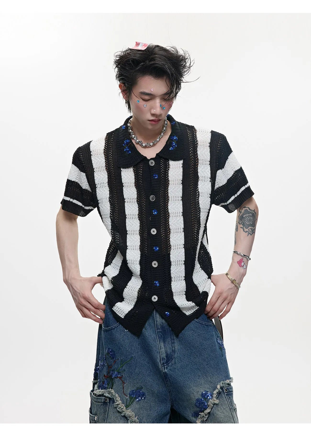Man wearing a red and black patchwork striped knitted short-sleeved shirt with a loose fit.
