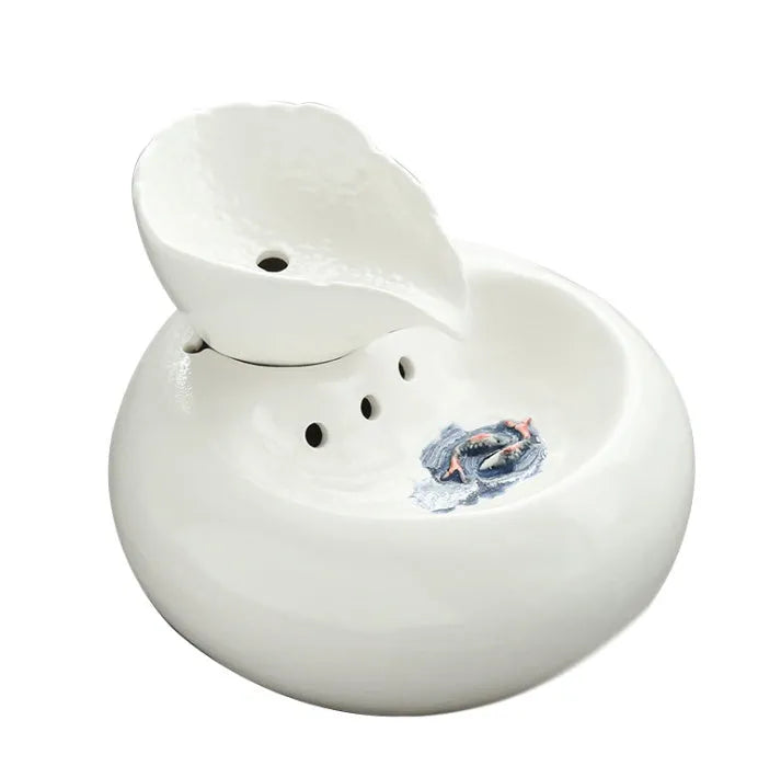 White ceramic automatic cat water dispenser with leaf design and US plug on a wooden floor