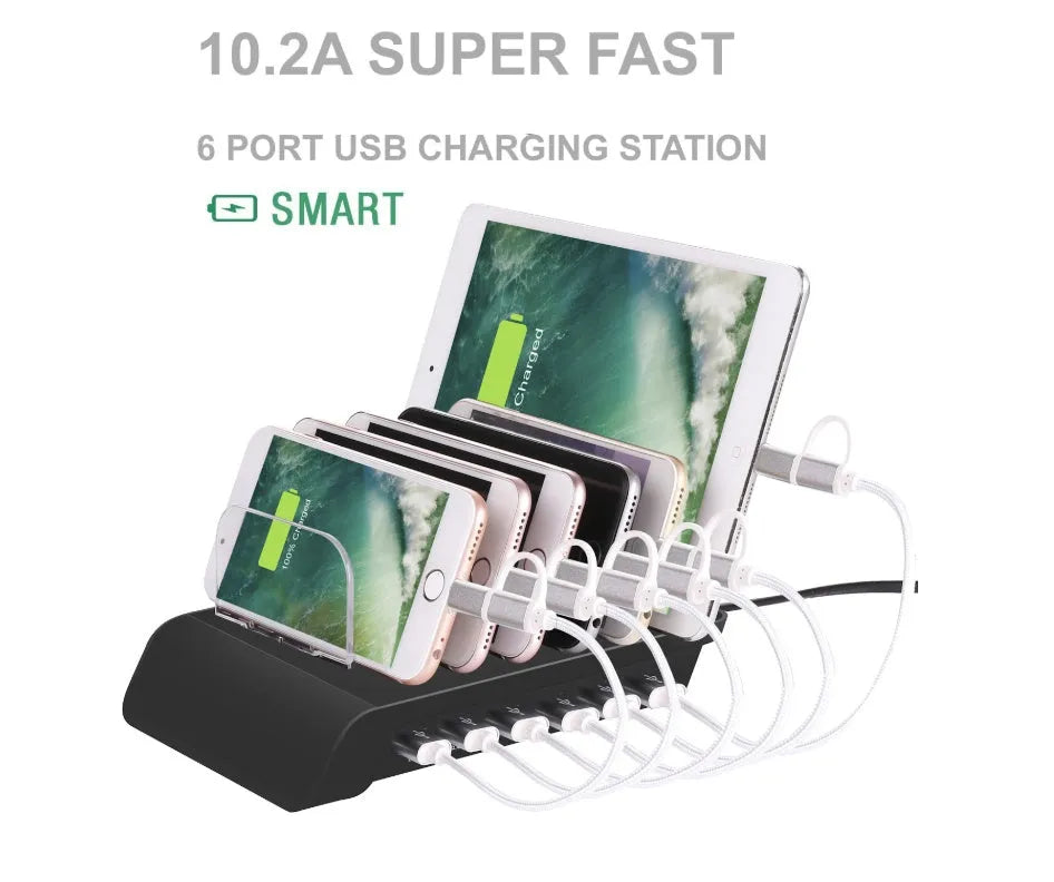 Six-port USB mobile phone charging stand in silver with multiple phones and tablets inserted, on a wooden desk
