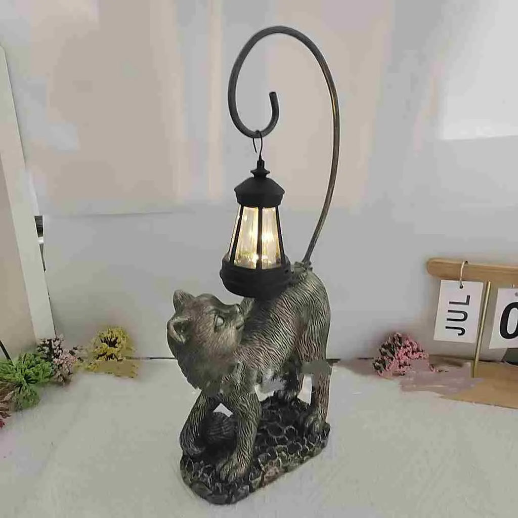 Bronze resin cat solar garden lamp on a garden path, outdoor decoration