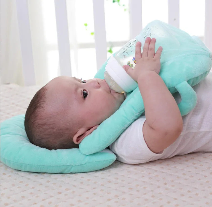 Pink plush baby feeding pillow on a carpet, showing its 30cm by 42cm size and soft texture.