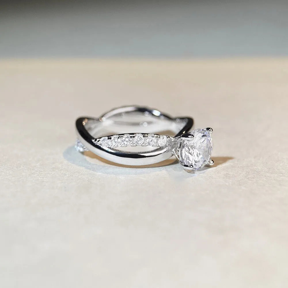 Silver ring with a 1 karat moissanite stone in a twisted four-claw setting, showing geometric lines and a cross design.