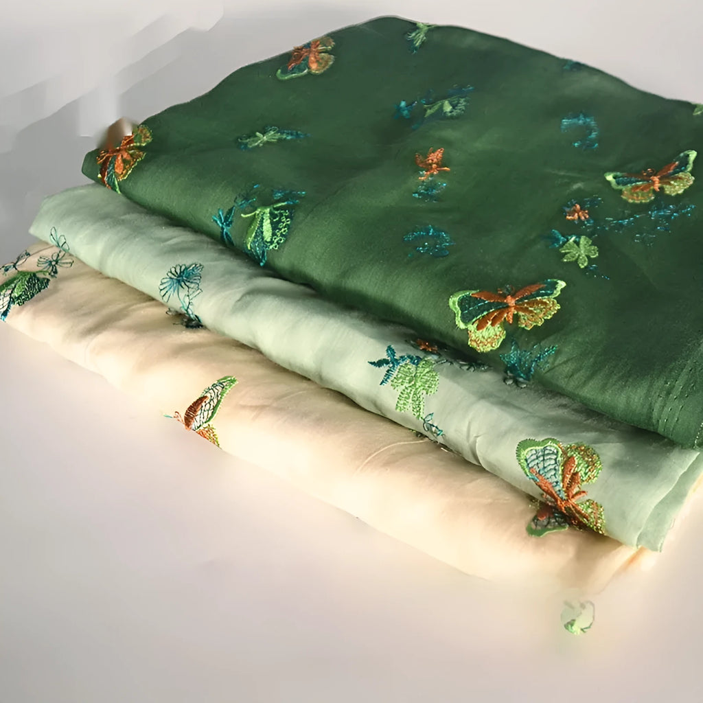 Close-up of pure ramie embroidery cloth in beige, dark green, and grass green colours, showing texture.