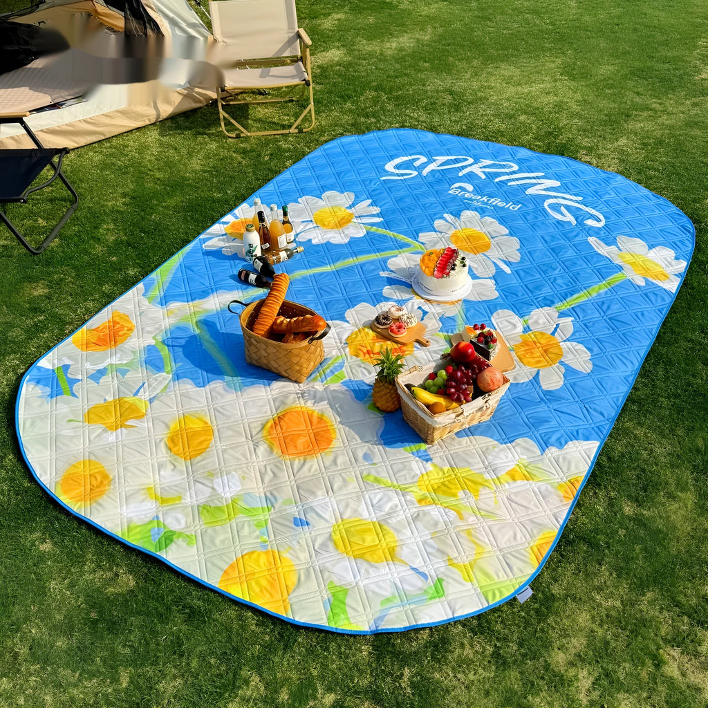 A large waterproof picnic mat in a seasonal colour, laid out on grass for a group.