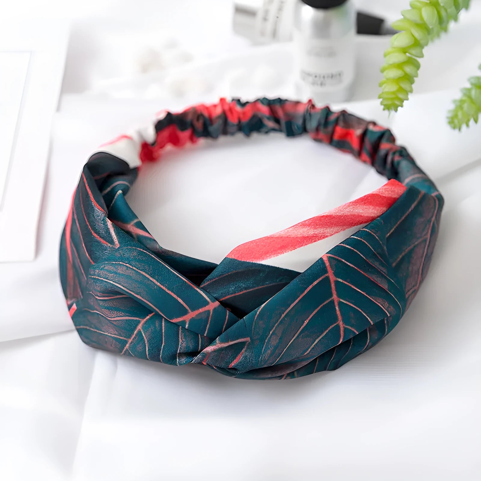 Red cloth headband with banana leaf and cross hair decorative pattern.