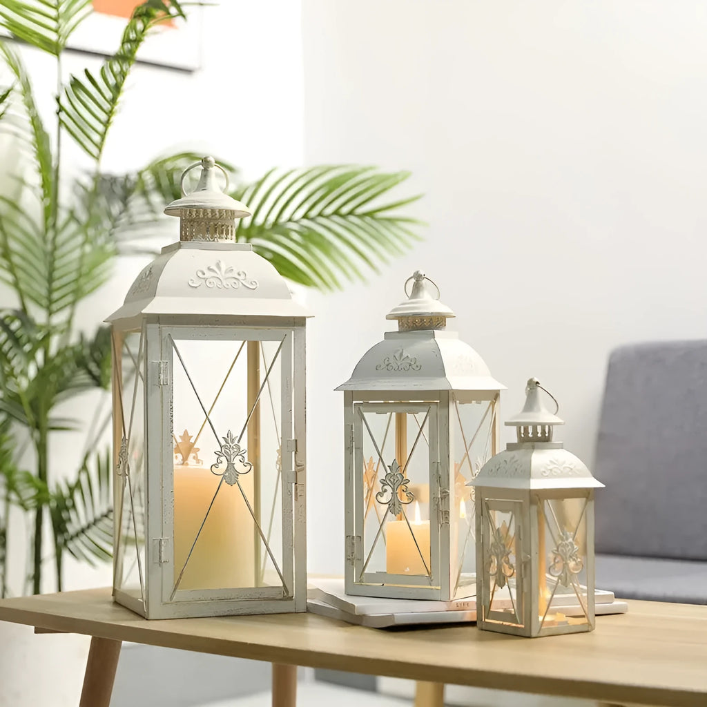 Black and white wrought iron floor-standing storm lantern with tempered glass panels in three sizes.