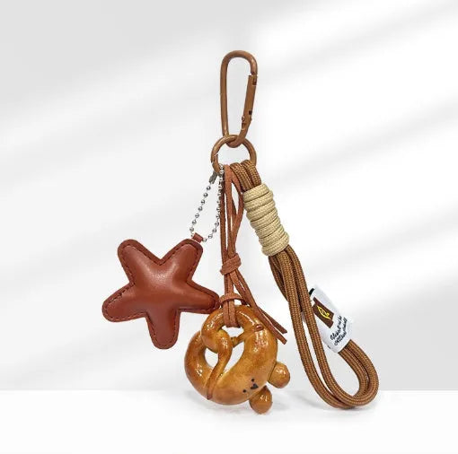 Handmade soda bread handbag charm pendant with cartoon croissant design and brown strap