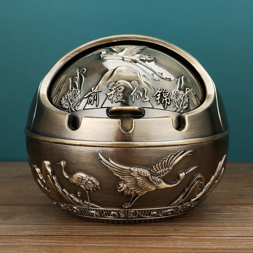 Alloy decorative ashtray in bronze with ornate peacock motif and cigarette extinguishing slot.