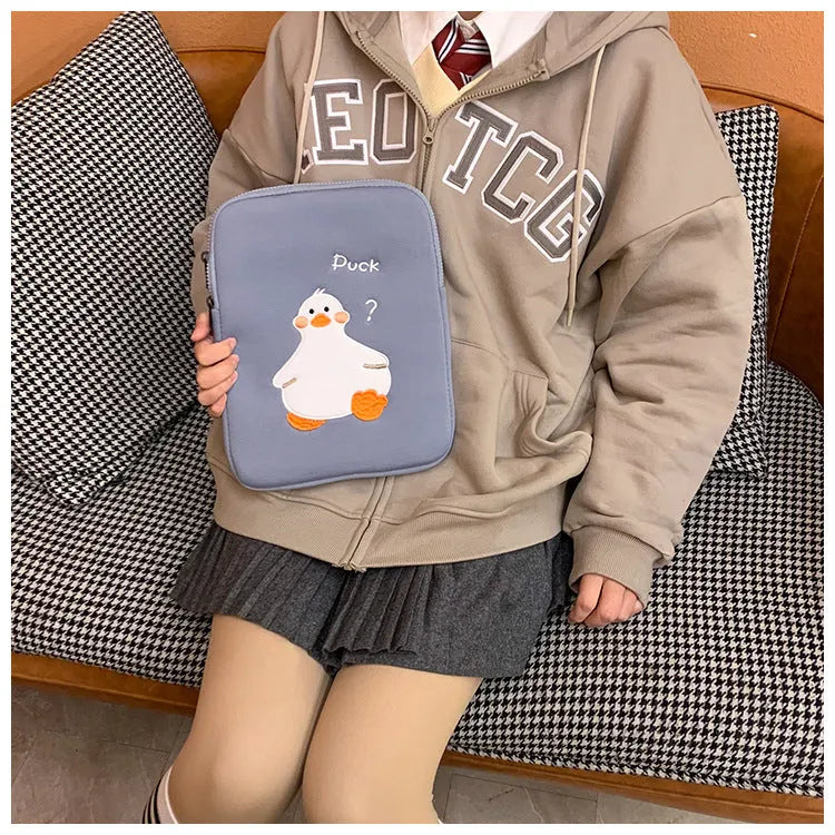 Blue cotton tablet case with embroidered cartoon duck design and a zipper closure, shown next to a green version.