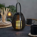 Oval rattan-style solar garden light in retro design for outdoor patio use.