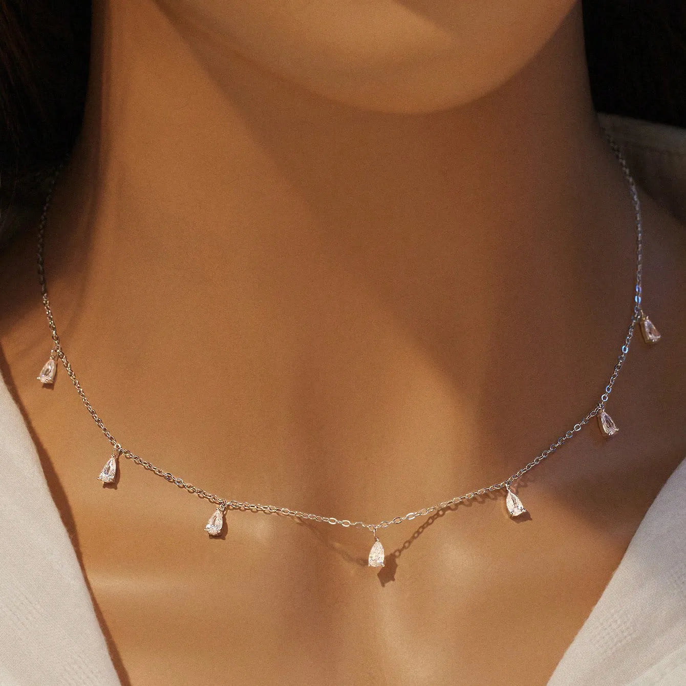 A drop-shaped sterling silver zircon pendant necklace on an O-chain, shown in silver, rose gold, and golden yellow finishes.