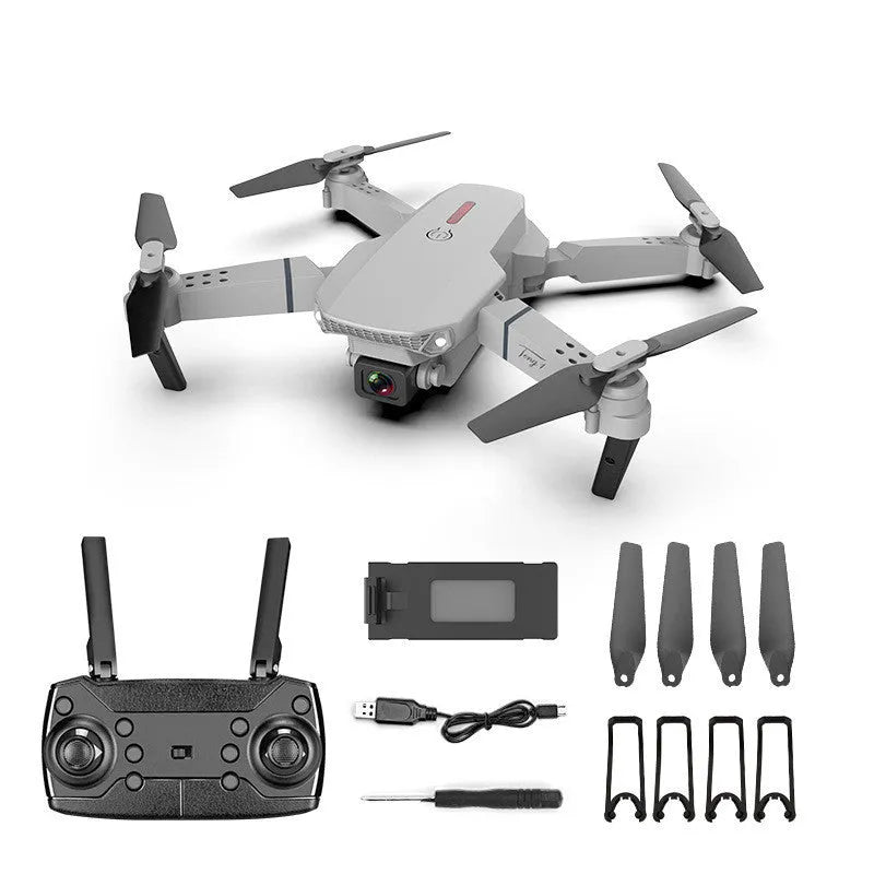 Grey foldable 4K dual camera drone with remote control, spare blades, and charging cable on a neutral background.