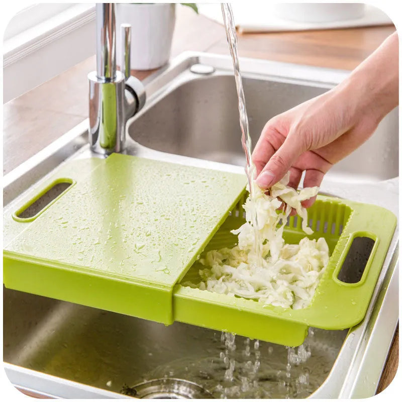 Blue kitchen chopping board with built-in sink drain basket and TPE handle on a counter.