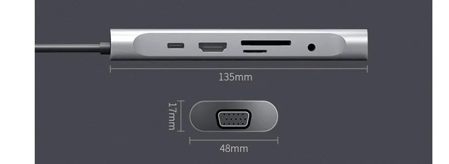 Grey aluminium USB-C docking station with HDMI, VGA, USB 3.0, and PD charge ports on a wooden desk.
