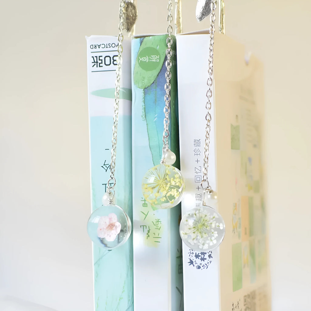 Close-up of a metal bookmark with a real dried dandelion sealed inside, showing 12cm length.