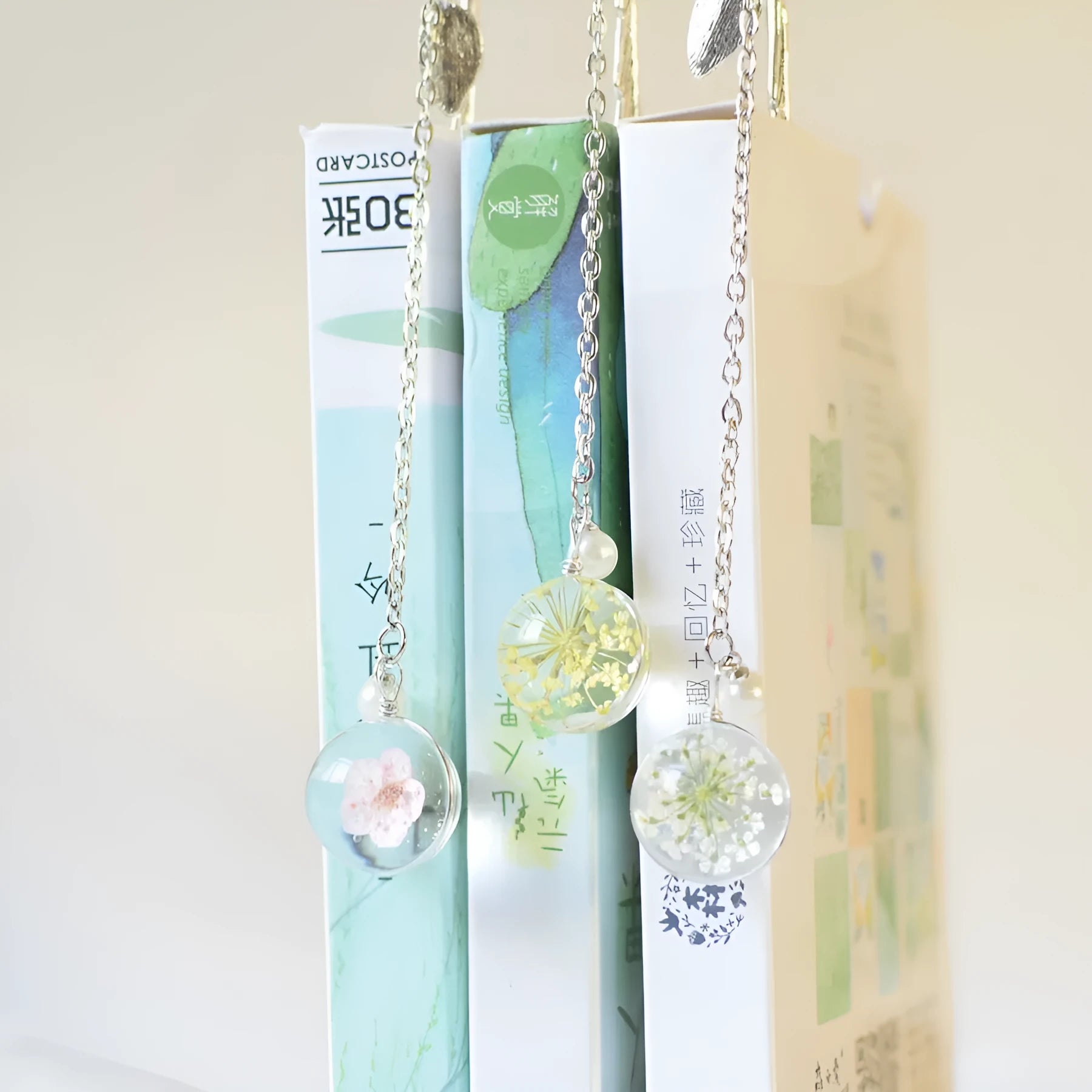 Close-up of a metal bookmark with a real dried dandelion sealed inside, showing 12cm length.